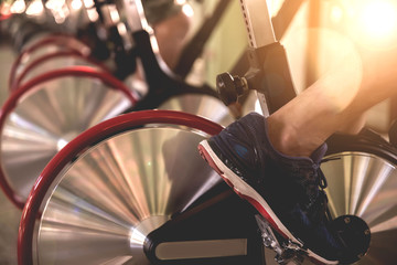 Good health  , Young People - group of women and men - doing sport biking in the gym for fitness /Health care concept/ Tone warm lights