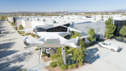 Fototapeta premium Unmanned Aircraft System Quadcopter Drone In The Air Near Corporate Industrial Building