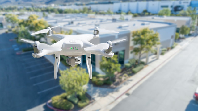 Unmanned Aircraft System Quadcopter Drone In The Air Near Corporate Industrial Building