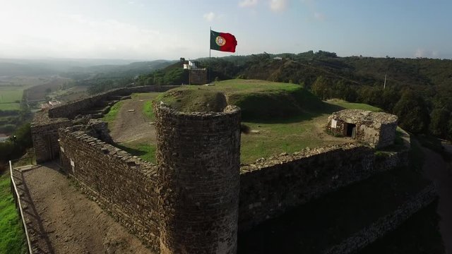 Portuguese flag waving in the wind on the top of a castle. Crane shot at the top of the hill