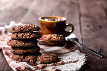 Cup of coffee and chocolate chip cookies on rustic wooden background.