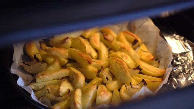 Roasted potatoes in oven with rosemary, olive oil and garlic.Baked potatoes with spices, unhealthy eating, fast food concept. Fried potatoes and overweight concept