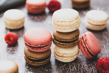 Heap of macarons isolated on dark background. Healthy cake dessert made from almond flour. Raspberry macaroons cookies.