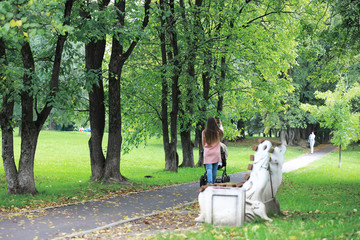 A young man in glasses walks in the park with an umbrella during the rain.