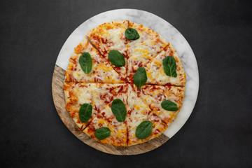 Delicious pizza on dark background, top view. Homemade round piza with cheese on dark background.