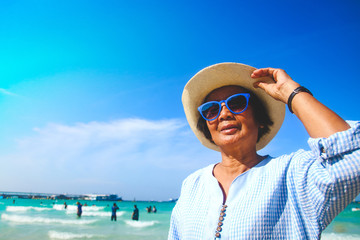 Asian elderly women Wearing blue sunglasses Walking around the sea