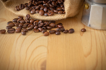 moka coffee machine, coffee beans and burlap sack on wooden background
