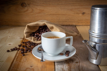 coffee in ceramic cup, moka coffee machine, coffee beans and burlap sack on wooden background