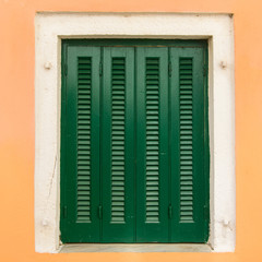 Window, green shutters against the yellow wall.