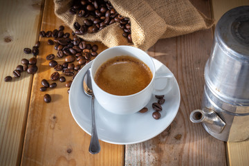 coffee in ceramic cup, moka coffee machine, coffee beans and burlap sack on wooden background