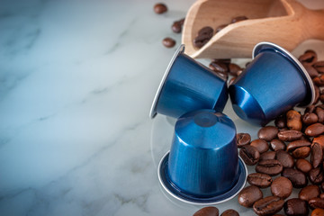 coffee beans and Italian espresso coffee blue capsules pods on a marble background