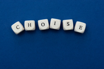 Choise word, lettering written on wooden blocks over blue background.