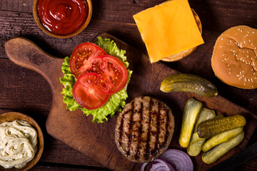 Preparation of fresh homemade burger on wooden table. Top view.