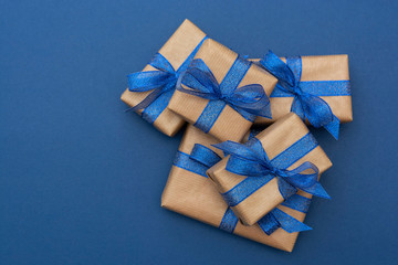 Christmas or birthday presents. Craft paper wrapped gift boxes on blue background, flat lay.