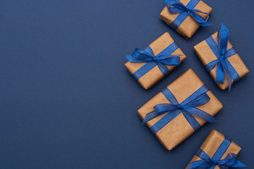 Christmas or birthday presents. Craft paper wrapped gift boxes on blue background, flat lay. Copy...