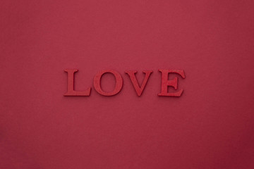 Fototapeta na wymiar LOVE lettering, 3D wooden red letters on red background. Creative Valentine's Day mock up. Love flat lay with word.