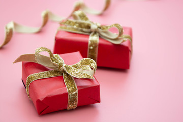 Red gift box and golden bow, on pink background. Valentine's Day, Birthday, Party concept.