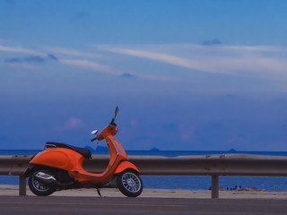 Orange motorbike parked by the sea.