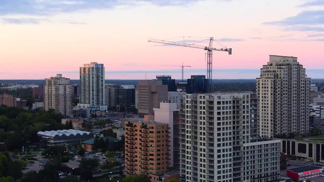 Aerial circling building tower crane downtown London Ontario during golden hour sunset