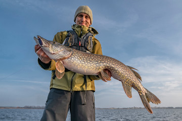 Happy fisherman with big pike fish. Boat fishing