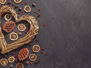 Golden wicker heart is on a dark texture background. Decorating with dried flowers and plants. Composition for Valentine's Day. Flat lay. Copyspace.