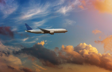 Airplane in the sky in dramatic sunset and sunrise sky.