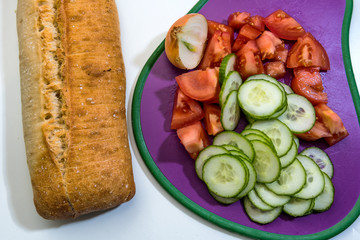 Fresh vegetables chopped in a cutting board - Salad ingredients - cucumber, tomatoes, cherry   tomatoes, onion, loaf of bread