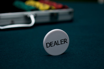 Dealer chip on green poker cloth in casino. Gambling concept