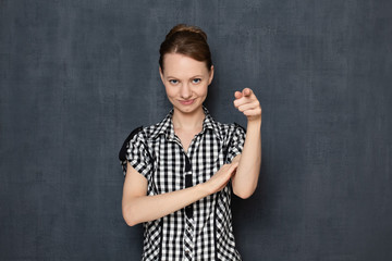 Portrait of happy young woman smiling and pointing with finger at you