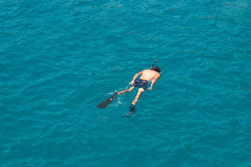 Man swims in the sea with a snorkel and a mask, diving.