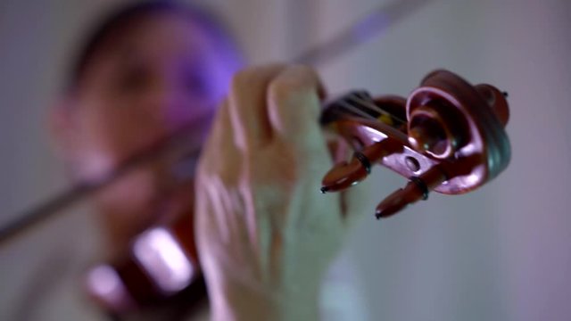 Close-up portrait and hands of a woman who plays the violin. It is in the room.