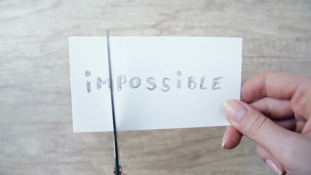 Man cutting word IMPOSSIBLE to read POSSIBLE. Concept of think positive, self belief and success of achievement