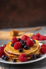 Sweet homemade pancakes with raspberries on white plate.