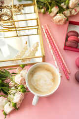 Flatlay pink coral background, the cup of cappuccino coffee and sweets macaroons, spring white roses, giftbox, beauty stuff - hair pin, nail polish and parfum. Best gift for woman