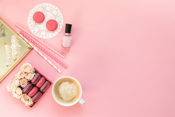Flatlay pink coral background, the cup of cappuccino coffee and sweets macaroons, spring white roses, giftbox, beauty stuff - hair pin, nail polish and parfum. Best gift for woman