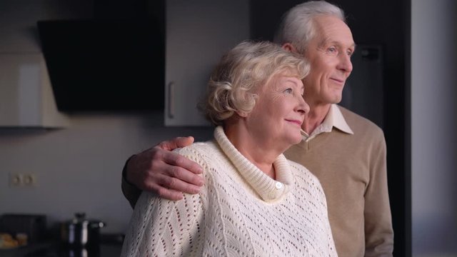 Senior man hugging wife, elderly married couple looking in happy future together