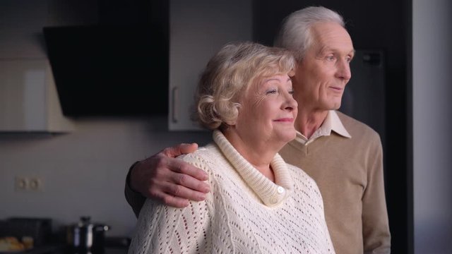Elderly couple smiling and looking in window, optimistic about future, insurance