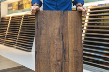 flooring store salesman with laminate floor sample panel in hands