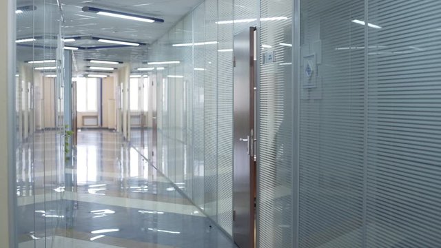 Caucasian Businessman in black suit walking along corridor to his office room