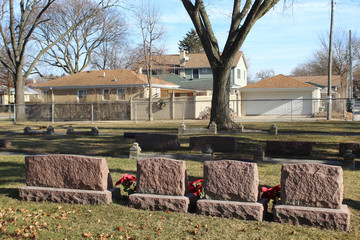 Four red granite gravestones with poinsettias at a tiny suburban Chicago cemetery