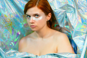 Portrait of a beautiful girl in shiny iridescent metallic fabric. girl wrapped in cloth. beauty...