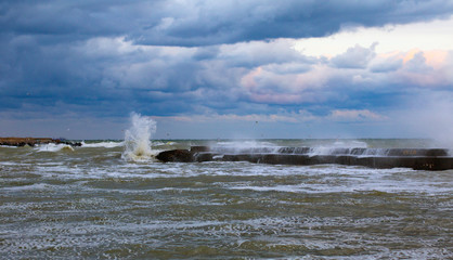 Naklejka na ściany i meble blue stormy clouds, storm at sea, waves are breaking of the pier, dirty orange water