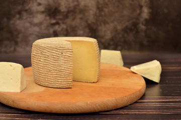 cheese head on a wooden board on a dark background