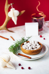 Cranberries in powdered sugar on the Christmas table with Christmas toys, branches of a green Christmas tree on a wooden plate with a bright festive background.