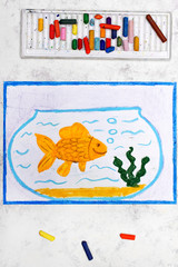 Photo of colorful drawing: Smiling goldfish in blue fishbowl. Fish with bubbles in glass