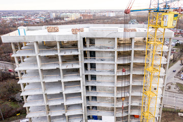 Photo of a multi-storey building under construction. Construction of a residential skyscraper. Background image of the process of building a house with cranes. A high-rise building under construction.