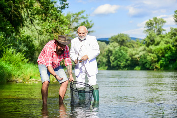 Simply being around. Two male friends fishing together. retired dad and mature bearded son. happy fishermen friendship. fly fish hobby of businessman. retirement fishery. Catching and fishing concept