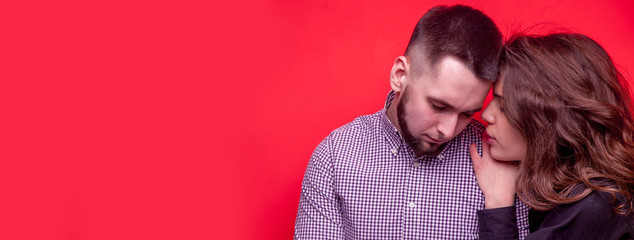 Romantic couple against red background. Portrait of beautiful girl and guy close to each other. Concept of tenderness and love