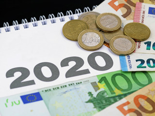 euro banknotes and coins on calendar 2020, concept of expenditure or taxes payment, cost in the new year