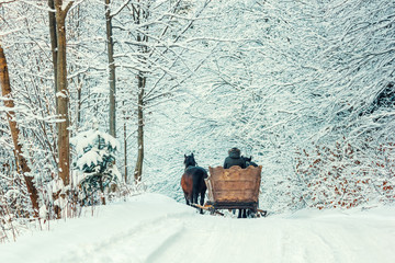 Winter landscape - view of the snowy road with with a horse sleigh in the winter mountain forest...